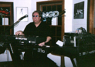 John Seppala at the keyboard, with an MGD neon sign in the background