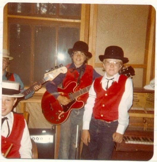 A young John Seppala on guitar with his band, in matching red vests and bowler hats