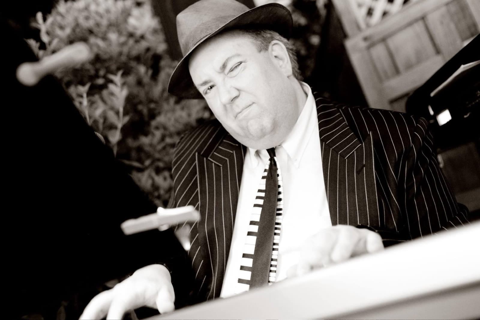 John Seppala performing at the keyboard, dressed in a pinstripe suit and hat