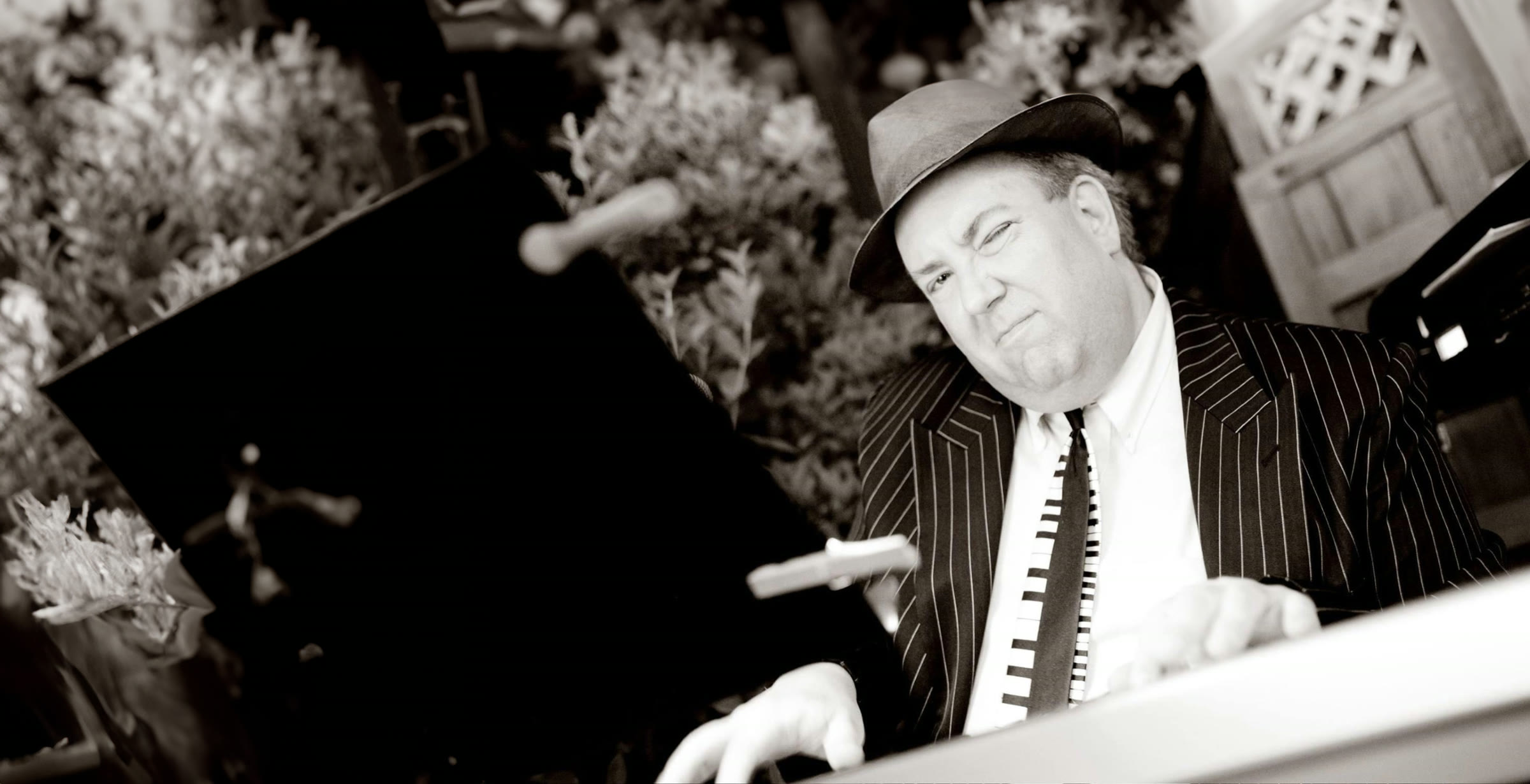 John Seppala performing at the keyboard, dressed in a pinstripe suit and hat